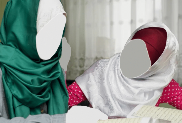Twee basisschool meisjes met het hoofddoek, gezamenlijk Koran aan het lezen.